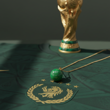 Load image into Gallery viewer, Green jade sphere pendant flat lay on soccer jersey with FIFA World Cup trophy – Healing Emerald
